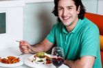 Young Smiling Man Eating At Restaurant Stock Photo