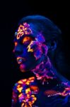 Beautiful Flowers In Uv Light On A Young Girl Face And Body Stock Photo