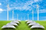 Solar Panels And Wind Turbine On Green Grass Field Against Blue Stock Photo