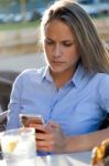 Beautiful Young Woman Using Her Mobile Phone In A Restaurant Ter Stock Photo