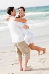 Young Couple Playing On Beach Stock Photo