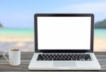 Laptop Computer And Coffee Cup Front Angle On Beach View Stock Photo