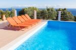 Row Of Orange Loungers Near Blue Swimming Pool Stock Photo