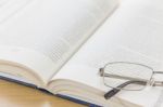 Close Up Glasses And Open Book On The Desk Stock Photo