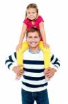 Fun Loving Kid Sitting On Her Father's Shoulders Stock Photo