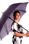 Side Pose Of Young Woman Holding An Umbrella Stock Photo