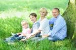 Cheerful Family Resting Under Tree Stock Photo