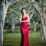 Beautiful Young Woman In The Gardens Wearing A Long Silk Red Dress Stock Photo