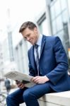 Smiling Businessman Reading Paper At Outdoors Stock Photo