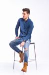 Male Model In Denim Jeans Sitting On A Chair . Studio Shoot Stock Photo