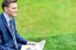 Businessman Reading Newspapers In Park Stock Photo