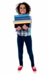 Cute Little Girl Carrying Stack Of Books Stock Photo