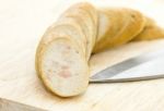 Sausage With Knife Over Cutting Board Stock Photo