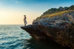 Young Woman Standing On The Top Of Rock And Looking At The Seashore And Sunset In Si Chang Island Stock Photo