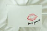 Sexy Girl Red Lips Kiss And "love You" Write On Blank White Note Paper On White Bed In The Morning Light.  Romantic Message From Couple Stock Photo