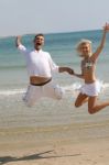 Young Couple Jumping At Beach Stock Photo