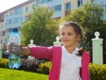 Girl Offering A Plastic Bottle With Water Stock Photo