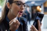 Beautiful Young Woman Making Up Using A Smart Phone As A Mirror Stock Photo