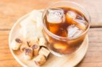 Glass Of Black Iced Coffee With Some Snack Stock Photo