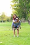 Full Length Of Happy Man Holding Happy Female On Back In Park Stock Photo