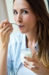 Young Woman At Home Eating Yogurt Stock Photo