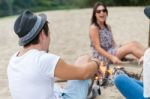 Young Adult Friends Hanging Around At Bonfire On Sandy Beach Stock Photo