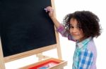 Beautiful Little Girl Writing On Classroom Board Stock Photo