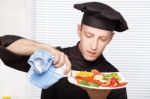 Chef Cleaning Edge Of Plate With Cloth Stock Photo