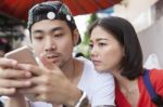 Asian Younger Man And Woman Watching On Smart Phone Use For People And Digital Technology ,wifi And Internet Connection Stock Photo