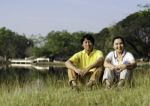 Portrait Of Beautiful Couple Sitting On Grass Stock Photo