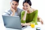 Happy Young Couple Browsing Internet At Home Stock Photo