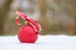 Red Christmas Bauble With Bow Outdoors In Snow Stock Photo