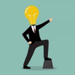 Businessman With A Light Bulb Head Pointing Up Stock Photo