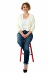 Aged Woman Sitting On Stool Stock Photo