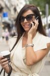 Young Brunette Laughs Into Phone Stock Photo