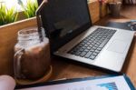 Coffee Cup  On A Table With Laptob And Graph Finance Diagram In Stock Photo