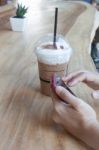 Woman Hand Holding Phone With Background Of Iced Coffee Stock Photo