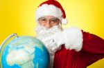 Santa Claus Selecting Location  On Globe Stock Photo