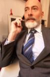 Middle-aged Businessman Listening On Smartphone At Home Stock Photo