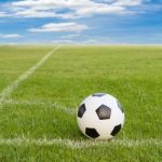 Soccer Ball On Soccer Field Against Blue Sky Stock Photo