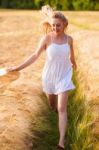 Happy Young Blonde Girl In White Dress With Straw Hat Running Th Stock Photo