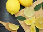 Fresh Lemon Juice In Small Bowl And Lemon Slice On Dark Wood Bac Stock Photo