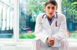 Portrait Of Serious Female Doctor With Hands Clasped Stock Photo