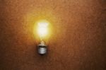 Glowing Bulb On The Brown Wooden Background Stock Photo