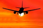 Silhouetted Commercial Airplane Flying At Sunset Stock Photo