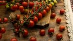 Cherry Tomatoes On Display On Wooden Chopping Board And Wooden Table Stock Photo