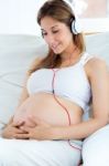 Pregnant Woman Sitting On Sofa At Home And Listening Music In He Stock Photo