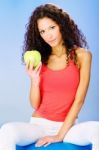 Women Seating On Blue Pilates Ball Holding Green Apple Stock Photo