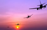 Silhouetted Commercial Airplane Flying At Sunset Stock Photo