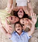 Happy Family Lying With Their Heads Close Together And Shouting Stock Photo